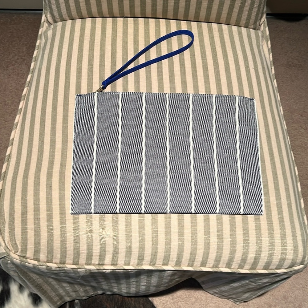 Rothy’s clutch bag in navy blue and beige with bright blue hand strap.